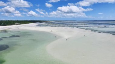 Dalgalar çekildiğinde adanın havadan görünüşü, okyanusta kumsal, beyaz kumlu plaj, insanlar, Zanzibar 'da güneşli bir yaz gününde mavi deniz. Üstten kumlu hava aracı manzarası, berrak su, bulutlu gökyüzü. Tropik