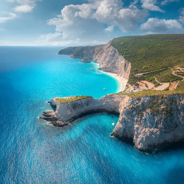 stock image Aerial view of blue sea, mountain cape, sandy beach, sky with clouds at sunrset in summer. Porto Katsiki, Lefkada island, Greece. Beautiful top view of sea coast, rocks, azure water, green forest