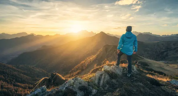 Tepedeki taş üstüne taş adam ve sonbaharda renkli günbatımında sisli güzel dağ vadisi. Dolomitler, İtalya. Guy, sisli dağ sırtları, turuncu çimenler ve ağaçlar, sonbaharda güneşli mavi gökyüzü. Yürüyüş