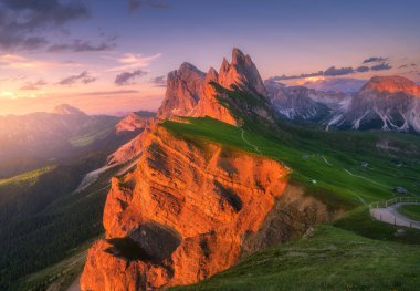 Dolomites, İtalya 'da yaz aylarında güzel bir günbatımında Seceda Dağı. Dağ zirveleri, kayalar, alp çayırları, patikalar, yeşil çimenler, bulutlu mor gökyüzü. Alplerde yürüyüş. Doğa