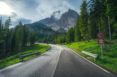 Yazın gün batımında Alp dağlarında yol. Dolomitler, İtalya. Güzel yol, yeşil kadın, bulutlardaki yüksek kayalar. Yaz aylarında dağ geçidinde içi boş otoban manzarası. Seyahat et. Aktarım