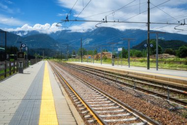 Güneşli yaz gününde Alp Dağları 'ndaki tren istasyonu. Demiryolu, yeşil ağaçlar, kayalar, mavi gökyüzü ile güzel bir sanayi manzarası. Dolomites, İtalya 'daki demiryolu platformu. Ulaşım. Tren istasyonu.