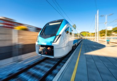 Yüksek hızlı mavi yolcu treni gün batımında tren istasyonunda hareket ediyor. Tren istasyonu. Bulanık hareket etkisine sahip modern demiryolu taşımacılığı konsepti. Demiryolu. Ticari ulaşım. Slovenya