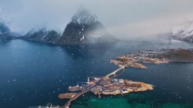 Karlı dağ zirveleri, deniz, köprü, yol, deniz manzaralı adalar, kışın dramatik gün doğumunda bulutlu gökyüzü. Hamnoy ve Reine 'in en iyi insansız hava aracı görüntüsü, Lofoten adaları, Norveç