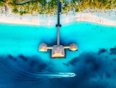 Bungalovun hava manzarası, yazın günbatımında Hint Okyanusu 'nda tekne. Deniz kıyısındaki restoran. Ahşap otelin en iyi insansız hava aracı manzarası, gök mavisi suyu, beyaz kumlu plaj, palmiye ağaçları. Kendwa, Zanzibar 'daki lüks tatil köyü.