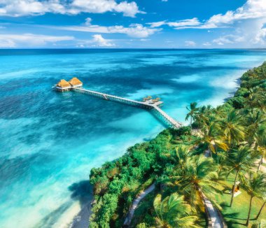 Bungalov, iskele, beyaz kumlu sahil, gün batımında okyanus manzarası. Zanzibar 'da yaz. Deniz kıyısındaki restoran. Ahşap otelin en iyi insansız hava aracı manzarası, gök mavisi suyu, yeşil palmiyeler, bulutlu gökyüzü. Lüks tatil köyü