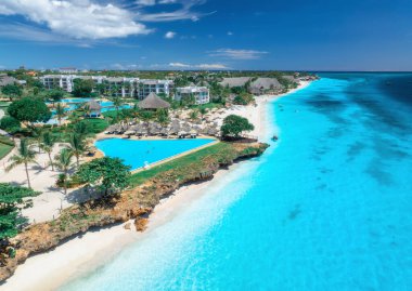 Havuz manzarası, palmiyeli beyaz kumlu plaj şemsiyeli, bungalovlu oteller, güneşli yaz günlerinde mavi okyanus. Nungwi, Zanzibar adasında tatil. Tropik bir manzara. Açık gök mavisi. Üst görünüm