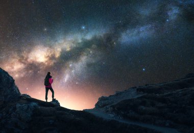 Parlayan Samanyolu ve yıldızlı gecede dağın zirvesinde bir kadın. Dolomitler, İtalya. Galaksi. Bir kızın siluetiyle uzay manzarası, kayalar, parlak yıldızlı gökyüzü. Samanyolu ve yürüyüşçü. Gece manzarası