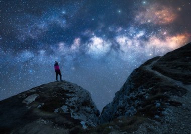 Parlayan Samanyolu ve yıldızlı gecede dağın zirvesinde bir kadın. Dolomitler, İtalya. Galaksi. Bir kızın siluetiyle uzay manzarası, kayalar, parlak yıldızlı gökyüzü. Samanyolu ve yürüyüşçü. Gece manzarası