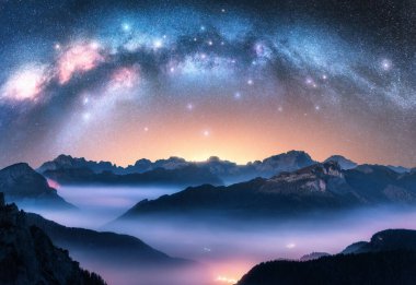Samanyolu geceleri alçak bulutlarda dağların üzerinde kemer gibidir. Alp Dağı Vadisi 'nin sisli manzarası. Samanyolu ile yıldızlı gökyüzü. Aydınlanma. Hava görüntüsü. Passo Giau, Dolomitler, İtalya. Boşluk. Üst görünüm