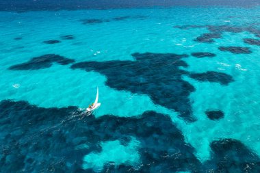 Güneşli yaz gününde mavi denizde yelkenli manzarası. Sardunya, İtalya 'ya seyahat. Yelkenli teknesi, deniz körfezi, şafak vakti şeffaf masmavi suyu olan tropik bir manzara. Yat manzaralı. Yat.