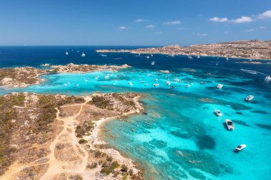 Lüks yatların ve mavi denizdeki teknelerin havadan görünüşü güzel bir ada, yaz güneşli bir günde dağ. Kumsal, kayalık deniz kıyısı, İtalya, Sardinya 'da masmavi şeffaf su. Üst dron görüntüsü. Deniz Burnu