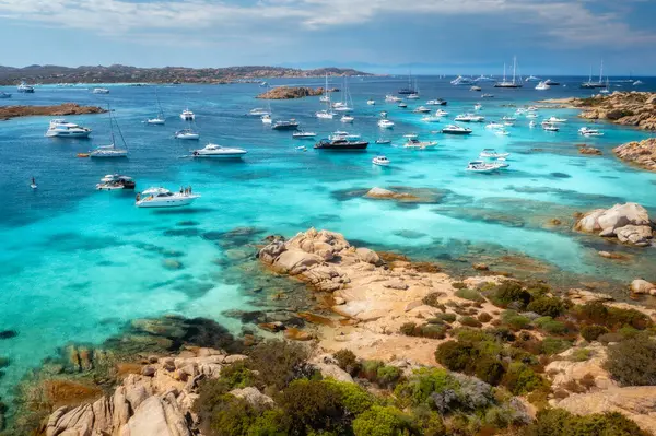 Sardunya, İtalya 'daki Maddalena takımadaları üzerinde nefes kesici bir hava manzarası var. Kayalık kıyı şeritleri ve yemyeşil bitki örtüsü arasında kristal berraklığında turkuaz sularda demirli lüks yatlar ve botlar var.