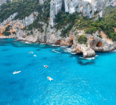 Yazın güneşli bir günde mavi denizdeki yat ve teknelerin hava manzarası. Cala Goloritze, Sardinya, İtalya. Deniz lagünü, sahil, şeffaf su, kayalar, orman, sahil manzarası. Üst dron görüntüsü. Deniz Burnu