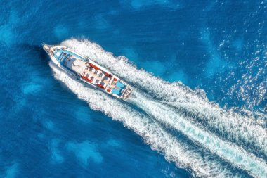 Yazın güneşli bir günde mavi denizde yüzen güzel bir yatın havadan görünüşü. Sardunya adası, İtalya. Hız teknesi, deniz kıyısı, şeffaf su. Seyahat et. Tropik bir manzara. Yat.