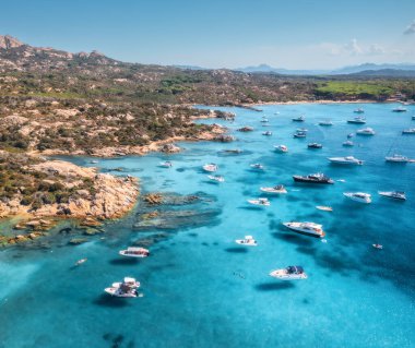 Lüks yatların ve mavi denizdeki teknelerin havadan görünüşü güzel bir ada, yaz güneşli bir günde dağ. Kumsal, kayalık deniz kıyısı, İtalya, Sardinya 'da masmavi şeffaf su. Üst dron görüntüsü. Deniz Burnu