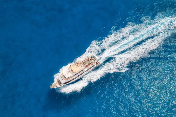 Yazın güneşli bir günde mavi denizde yüzen güzel bir yatın havadan görünüşü. Sardunya adası, İtalya. Hız teknesi, deniz kıyısı, şeffaf su. Seyahat et. Tropik bir manzara. Yat.