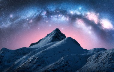 Samanyolu kışın yıldızlı gecesinde güzel karlı dağın üzerinde. Lofoten Adaları, Norveç. Pembe gökyüzü, parlayan Samanyolu kemeri ve yıldızları, karlı kayaları olan renkli bir manzara. Boşluk. Doğa arka planı