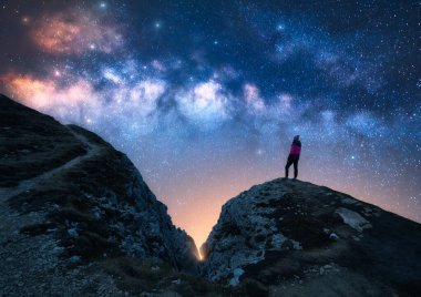 Parlayan Samanyolu ve yıldızlı gecede dağın zirvesinde bir kadın. Dolomitler, İtalya. Galaksi. Bir kızın siluetiyle uzay manzarası, iz, kayalar, parlak yıldızlı gökyüzü. Samanyolu ve yürüyüşçü. Gece manzarası