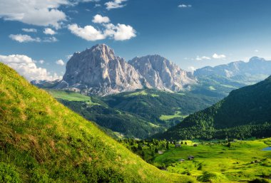 Gün batımında Alp Dağı Vadisi 'nin havadan görüntüsü. İtalya 'da yaz mevsimi. Dağ zirveleri, çayırlar, yeşil çimenli tepeler, evler, bulutlu mavi gökyüzü. Doğa. Üst görünüm