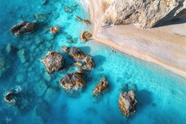 Mavi denizin havadan görünüşü, berrak sulardaki kayalar, yazın günbatımında beyaz kumlu plaj. Porto Katsiki, Lefkada Adası, Yunanistan. Deniz kıyıları olan güzel bir manzara, gök mavisi sulardaki taşlar, dalgalar. Üst görünüm