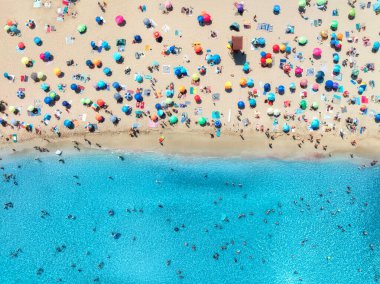 Kalabalık kumlu sahillerde renkli şemsiyeler, güneşli yaz günlerinde mavi denizde yüzen insanlar. Mallorca, Balear Adaları, İspanya. Tropik bir manzara. Turkuaz suyla manzara. Seyahat