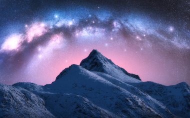 Samanyolu kışın yıldızlı gecesinde güzel karlı dağın üzerinde. Lofoten Adaları, Norveç. Parlayan Samanyolu kemeri, yıldızları, karlı kayaları ve uzayı olan pembe gökyüzü ile renkli bir manzara. Doğa