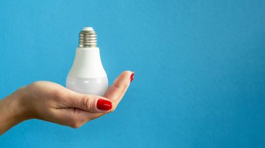 Bir kadının elindeki lamba. LED lamba tutan kadın parmakları. Bir fikrim var. Yeni fikir ya da ilham konsepti. Başlangıç konsepti. mavi arka plan. Yatay resim.