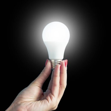 lamp in a woman's hand. female fingers holding LED lamp. idea. New idea or inspiration concept. Concept of startup. Square image.