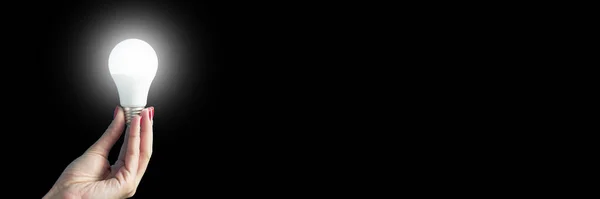 lamp in a woman's hand. female fingers holding LED lamp. idea. New idea or inspiration concept. Concept of startup. Banner for insertion into site. Horizontal image.