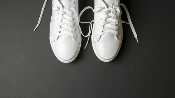 黑色底色的白色皮鞋 白色运动鞋 白色鞋带 新鞋子横向图像 — 图库照片