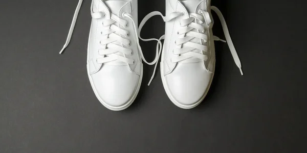 黒の背景に白い革の靴 白いレースの白いスニーカー 新しい靴だ 水平像 — ストック写真