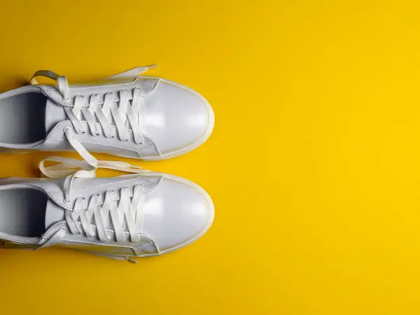 黄色の背景に白い革の靴 白いレースの白いスニーカー 新しい靴だ 水平像 — ストック写真