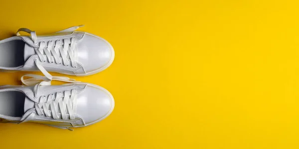 黄色の背景に白い革の靴 白いレースの白いスニーカー 新しい靴だ 水平画像 サイトへの挿入用バナー — ストック写真