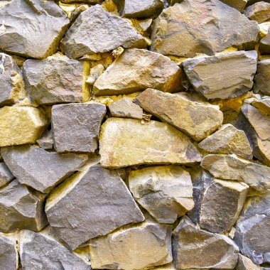 Close-up image of the wall. Rough, natural stone texture. Stone of different sizes and shapes. Template for interior design, websites or promotional materials. Square image.