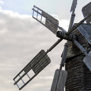 Photo of a windmill, taken in a picturesque rural landscape. A stationary windmill in windless weather. Square image.