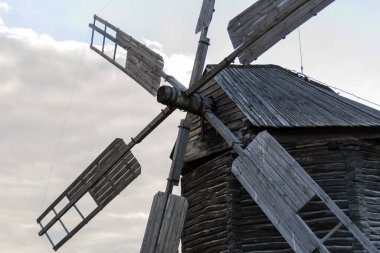 Photo of a windmill, taken in a picturesque rural landscape. A stationary windmill in windless weather. Horizontal image.