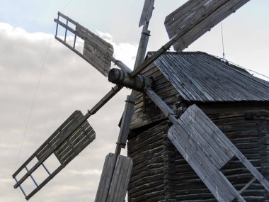 Photo of a windmill, taken in a picturesque rural landscape. A stationary windmill in windless weather. Horizontal image.
