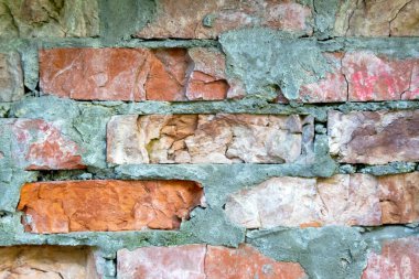 An image of the texture of a brick wall with a coarse-grained, embossed surface. Small cracks and cement inclusions. Horizontal image.