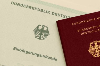 NUREMBERG, GERMANY 17 Ocak 2025: Resmi bir vatandaşlık belgesine (Einbrgerungsurkunde) yerleştirilmiş bir Alman pasaportunun yakın çekimi. Alman vatandaşlığının başarılı bir şekilde kazanılması için sembolik. Sadece yazı işleri için..