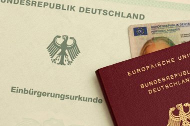 NUREMBERG, GERÇEK 22 HAZİRAN 2025: Resmi bir vatandaşlık belgesinde bir Alman pasaportu ve kimlik kartının yakın çekimi. Alman vatandaşlığının başarılı bir şekilde kazanılması için sembolik. Sadece yazı işleri için..