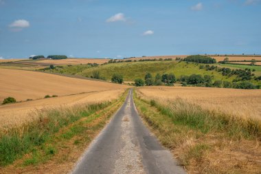 Road leading into the Yorkshire Wolds with hills and blue sky on a clear sunny day. clipart