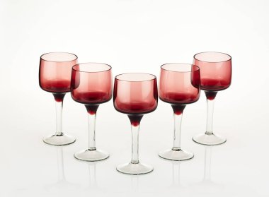 Uzun saplı, zarif kırmızı şarap kadehlerinin yakın çekimi, ürün sunumu için temiz beyaz arka planda profesyonelce izole edilmiş..