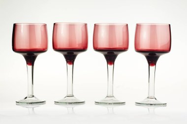 Uzun saplı, zarif kırmızı şarap kadehlerinin yakın çekimi, ürün sunumu için temiz beyaz arka planda profesyonelce izole edilmiş..