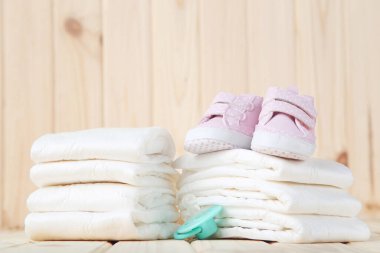 Emzik ve kahverengi tahta arka planda bir çift ayakkabılı bebek bezi.