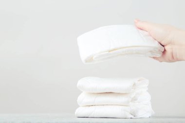 Gri arka planda kadın eli olan bebek bezleri.