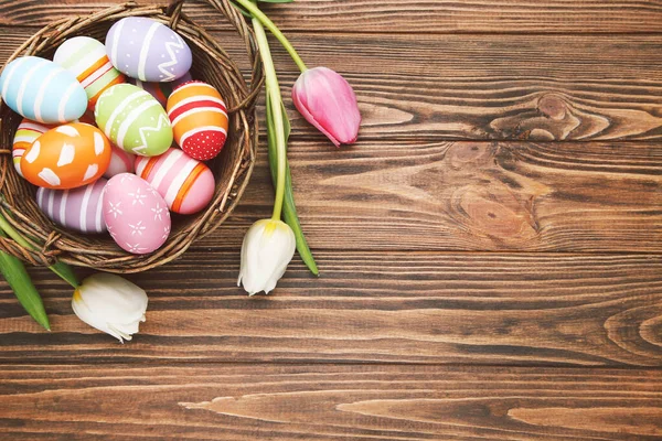 Kleurrijke Eieren Mand Bloemen Van Tulpen Bruine Houten Ondergrond — Stockfoto