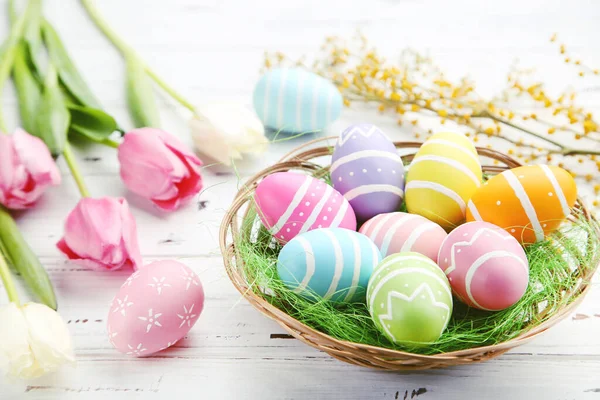 Colorful Eggs Basket Flowers Mimosa Tulips White Wooden Background — Stockfoto