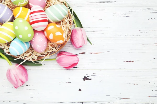 Bunte Eier Korb Und Blumen Von Tulpen Auf Weißem Holzgrund lizenzfreie Stockbilder
