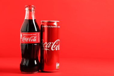 MYKOLAIV, UKRAINE - 22 Ocak 2021: Coca-Cola kutusu ve kırmızı arka planda cam şişe